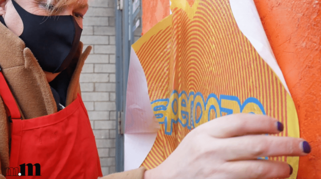 Koko Bayer wears a red apron while she puts up one of her yellow and red "Esperanza" hearts.