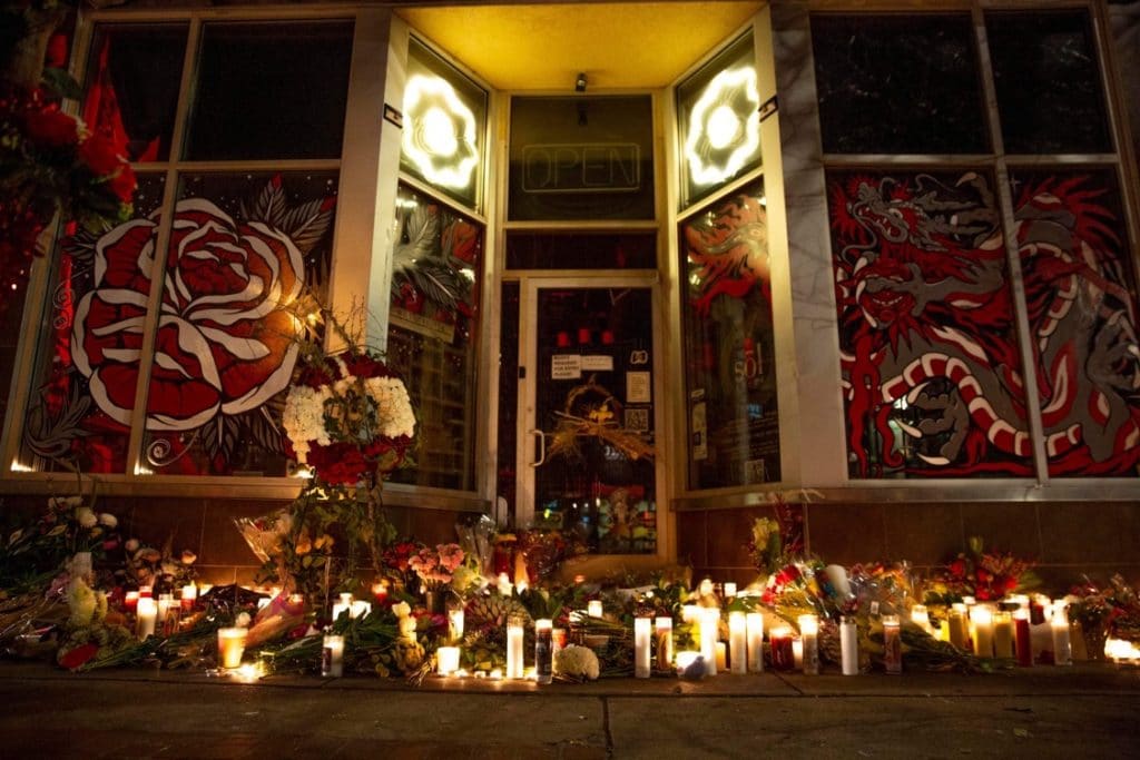 Candles and flowers cover the sidewalk in front of Sol Tribe Tattoo & Body Piercing in Denver the night of Dec. 28.